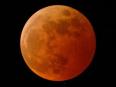 地球の大気を透過した太陽光が投影されて赤く輝く月面／NASA